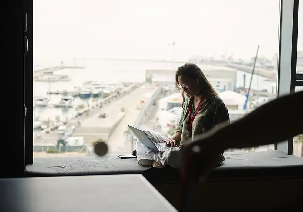 Kvinde sidder i vindue på computer