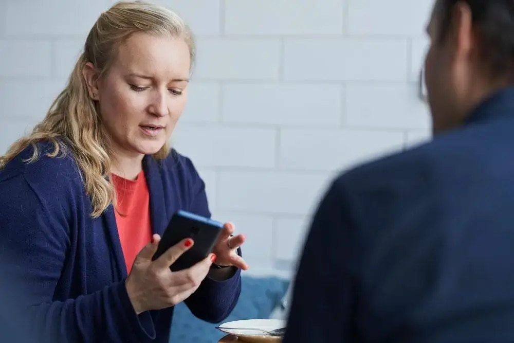 kvinde viser mand Intega Go på sin telefon