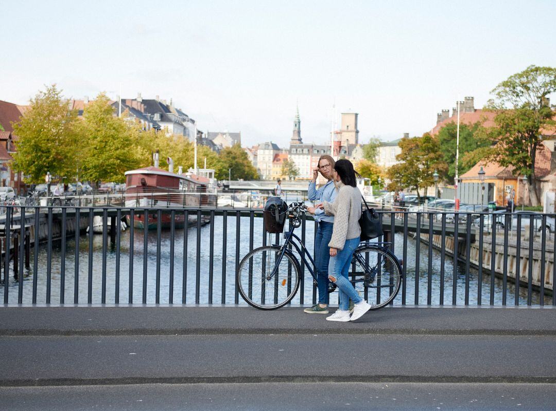 To kvinder på en bro med cykel